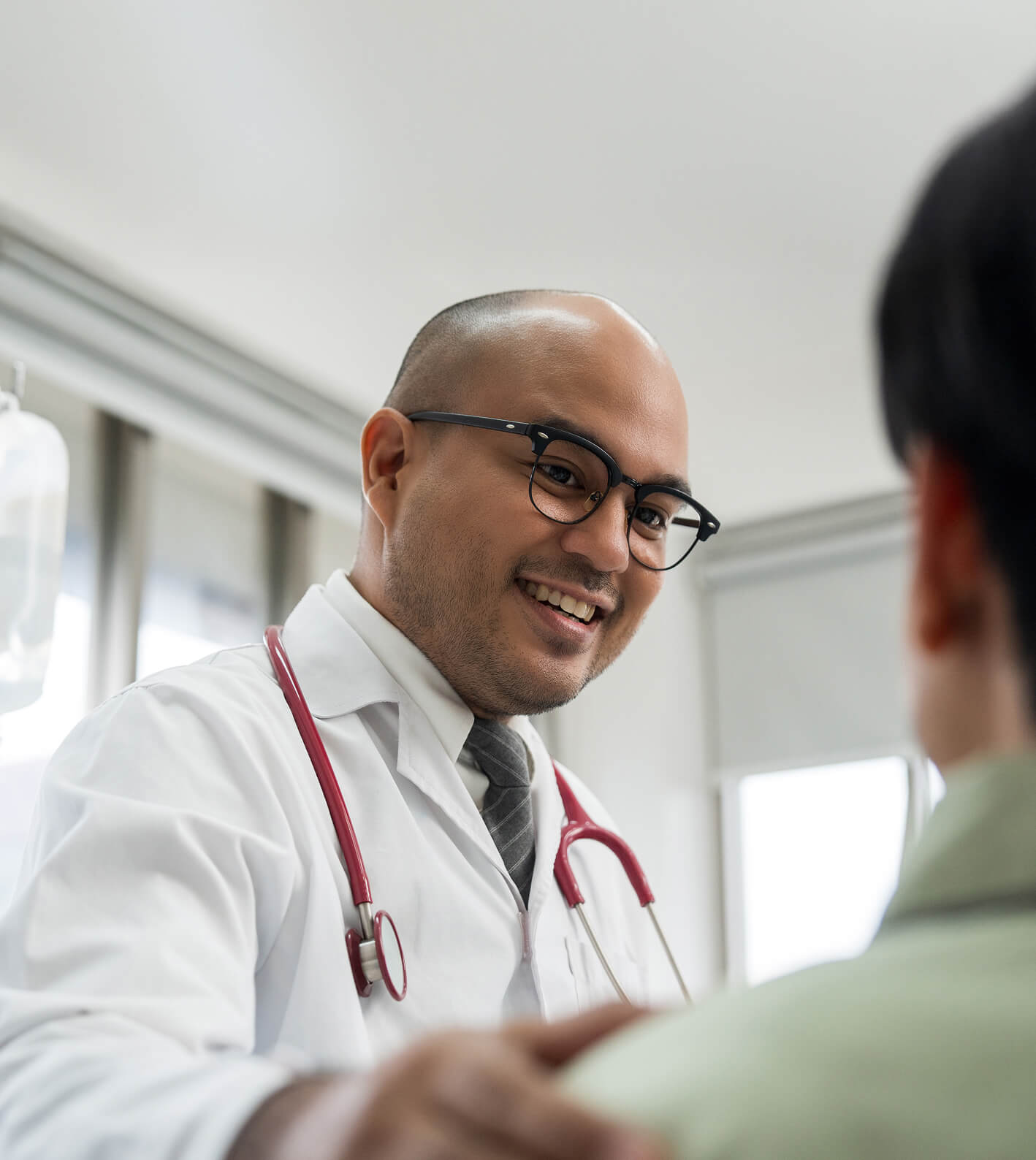 A smiling physician clasps a patient on the shoulder.